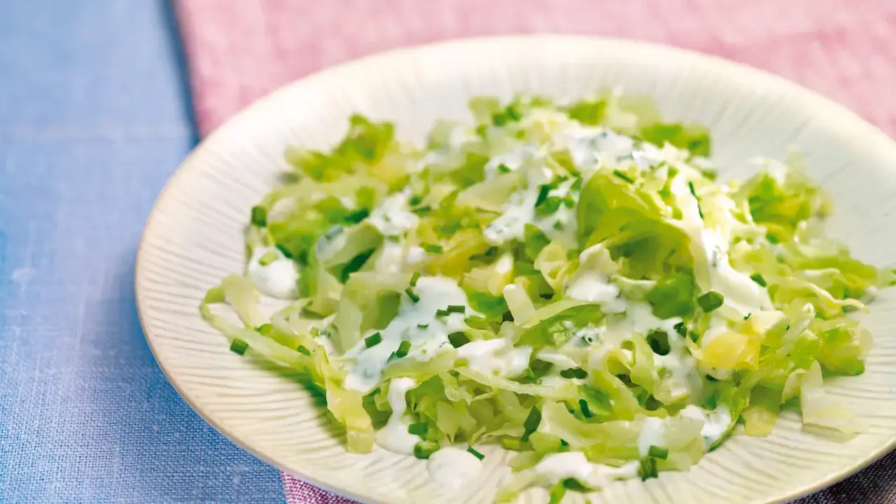 Frischer Spitzkohlsalat mit cremigem Dressing und Schnittlauch auf einem Teller.